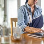 Woman with Injured arm at laptop