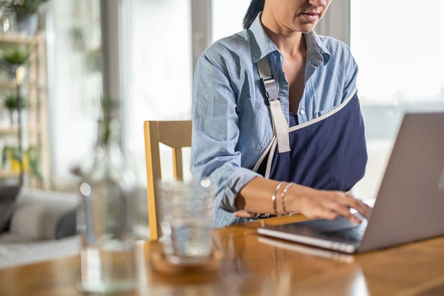 Woman with Injured arm at laptop