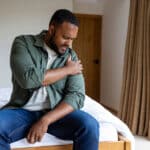 Man with sore shoulder in bedroom