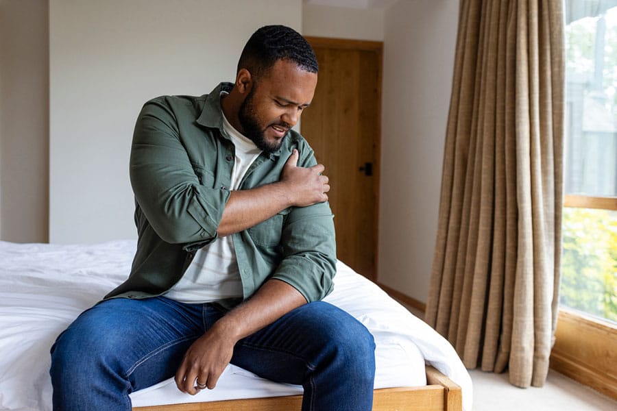 Man with sore shoulder in bedroom